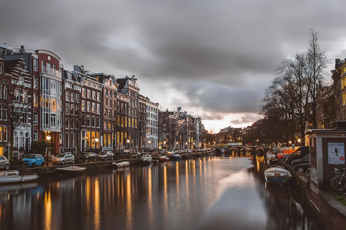 An Amsterdam canal lined with historic buildings at dusk